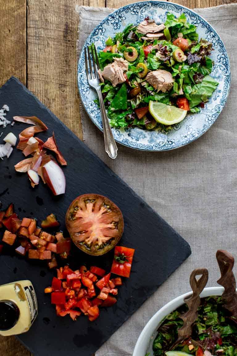 Tuna Green Salad in a serving plate on a table alongside a cutting board