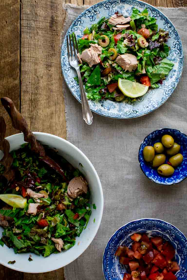 Tuna Salad with Lettuce and Tomato in serving bowls alongside extra olives and tomatoes