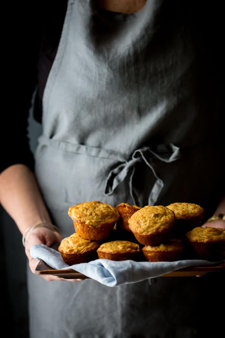 a person holding a tray of savory muffins