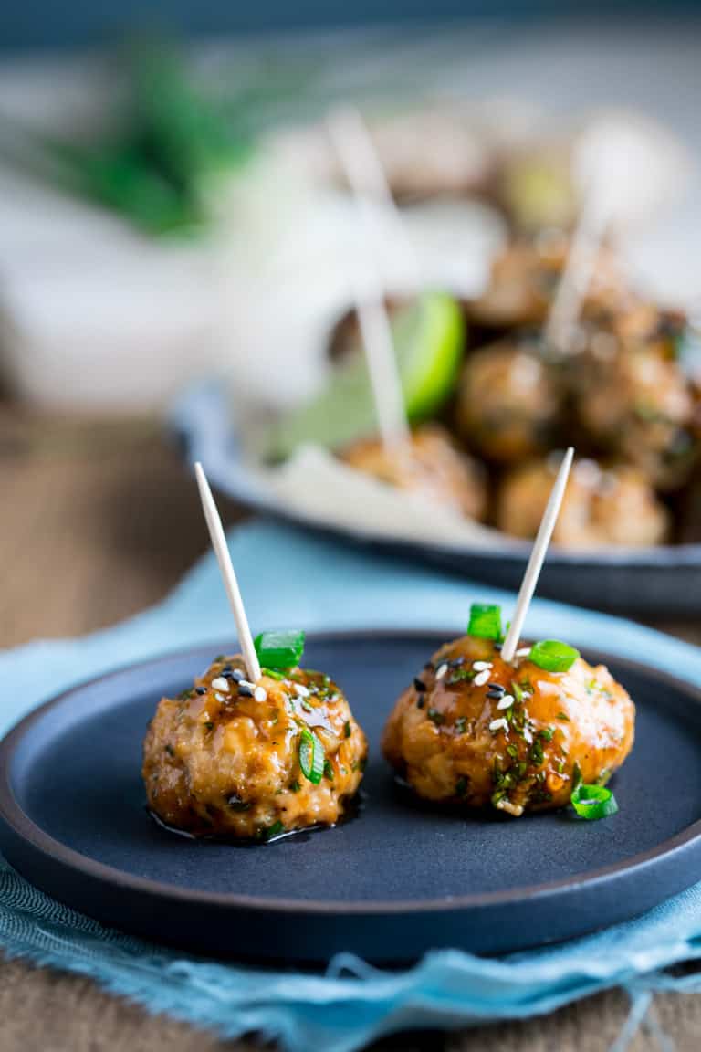 two meatballs on a black plate with toothpicks