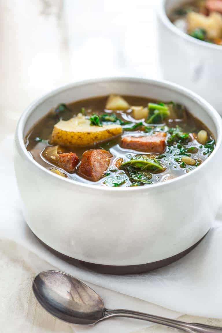 a white bowl filled with soup with a spoon in the foreground