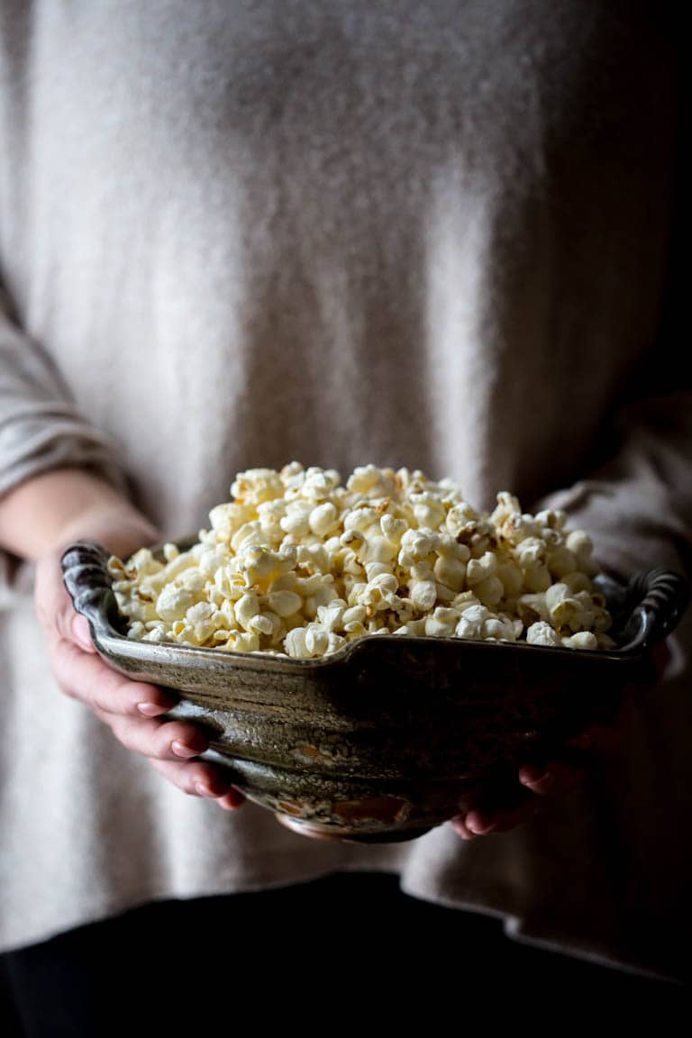holding a large bowl of stovetop popcorn