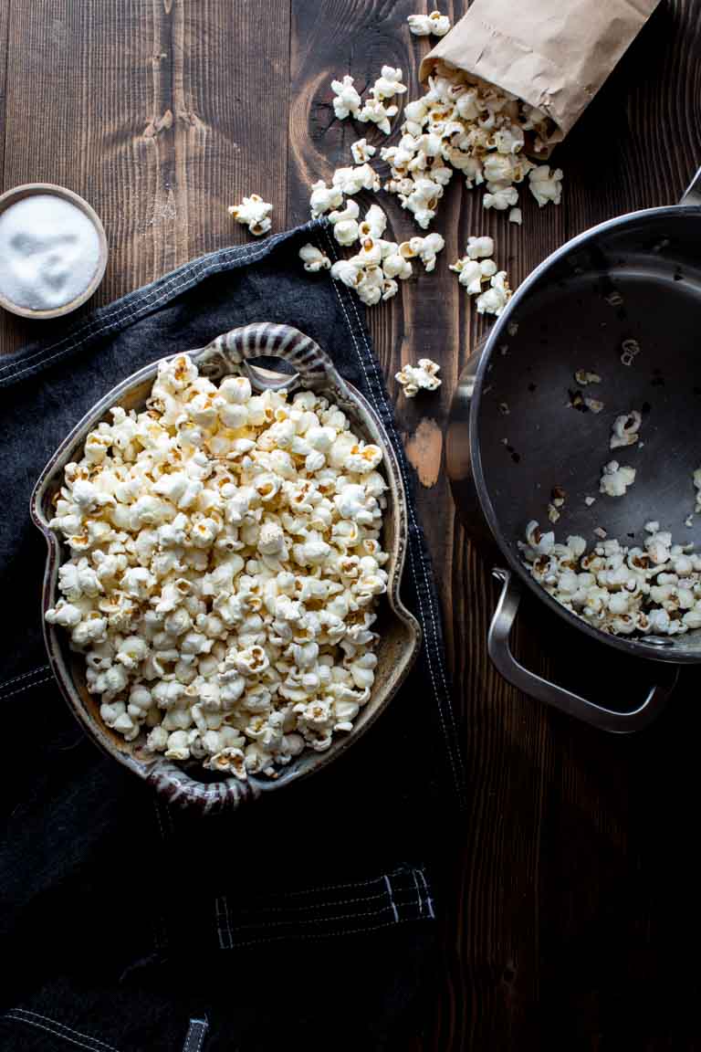 stovetop popcorn in a bowl next to a bag of popcorn