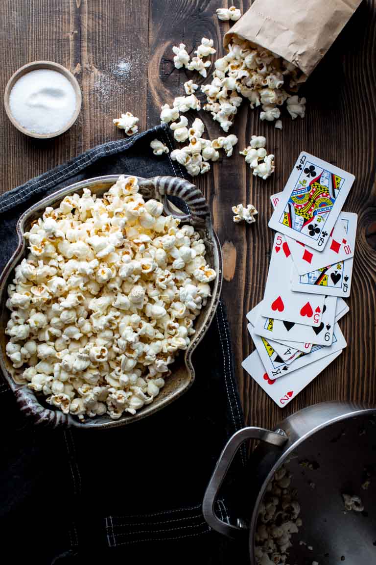 stovetop popcorn in a large bowl next to playing cards