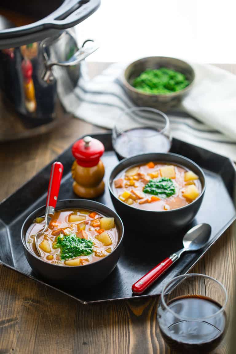 ham and barley soup served in bowls with a dollop of spinach pesto while sitting beside the slow cooker