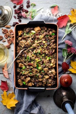 a table with autumn leaves and a casserole dish of stuffing