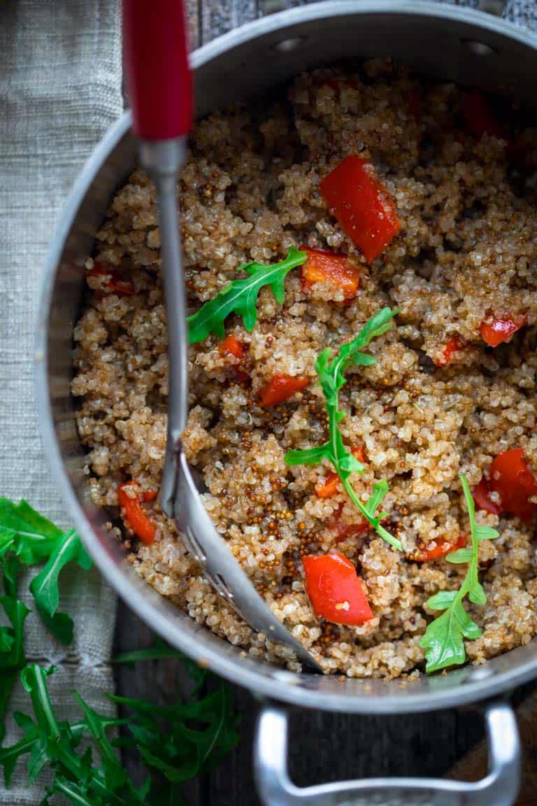 Warm Quinoa Arugula Salad in a pot with a serving spoon