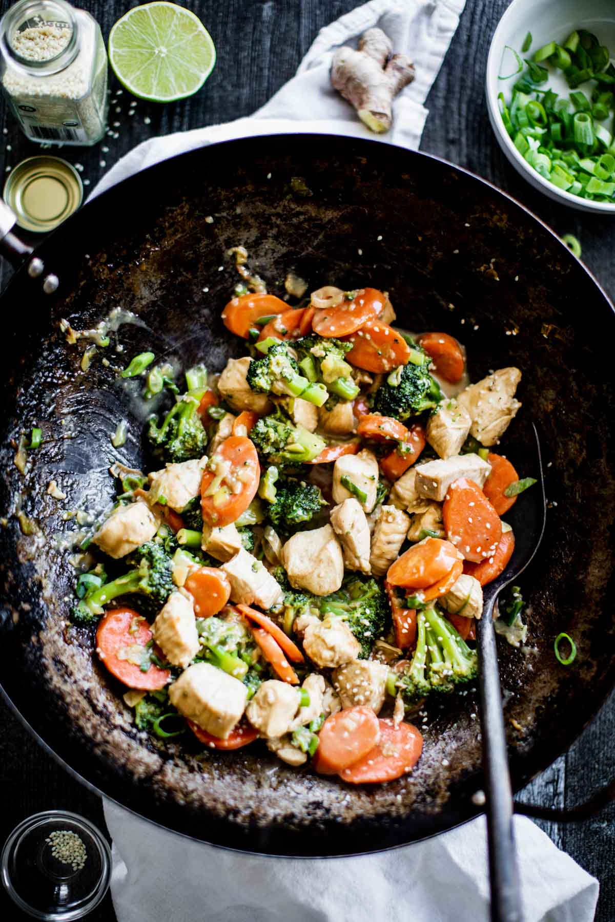 overhead of the wok with the stirfry on a table with lime and sesame seeds