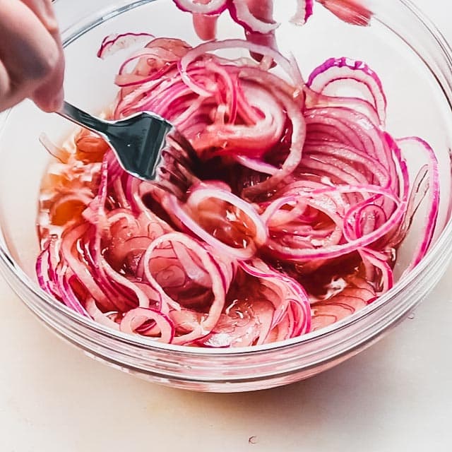 tossing the onions in the brine with a fork