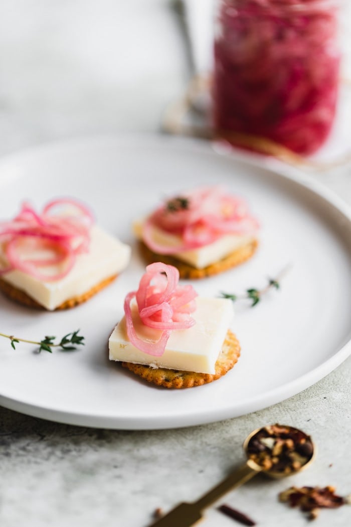 cheese and crackers with pickled onions on top