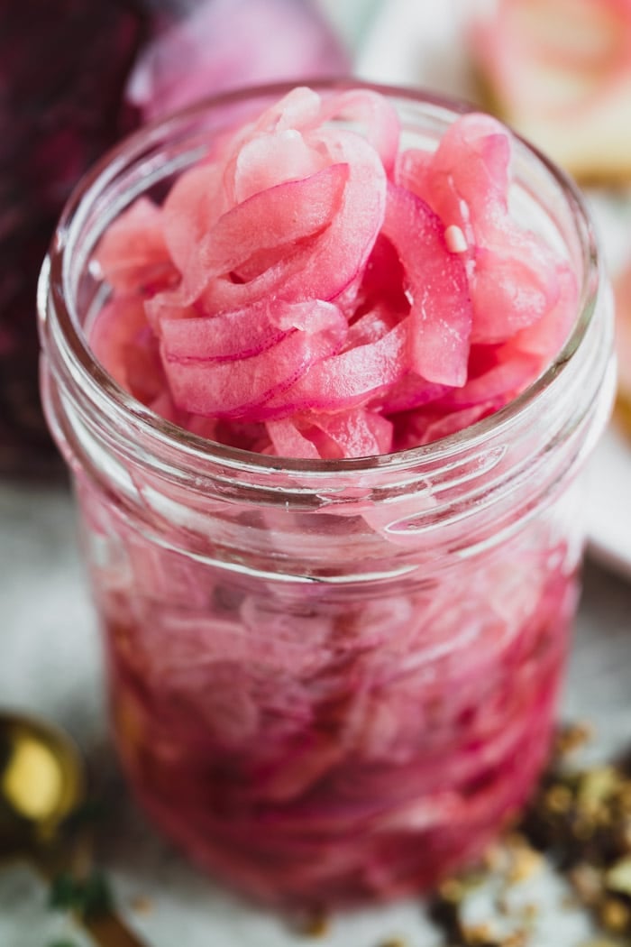 a close up of a jar of pickled onions