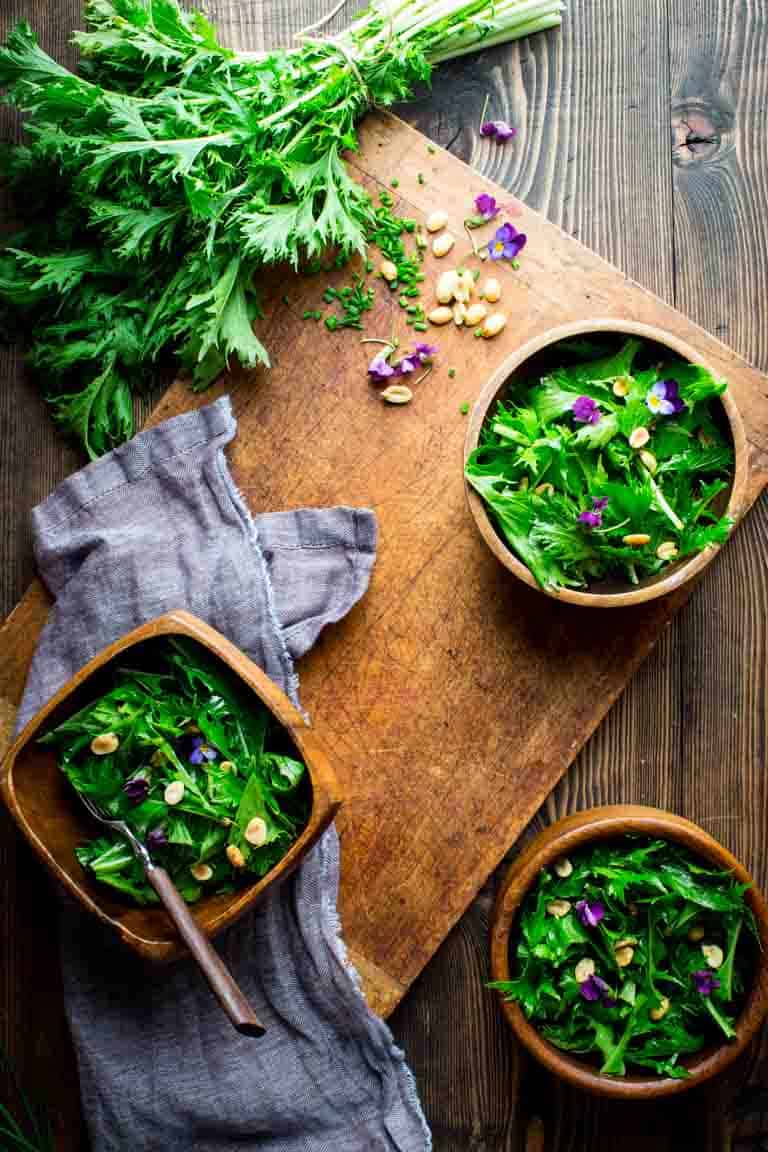 Mizuna Salad in three serving bowls on a cutting boards