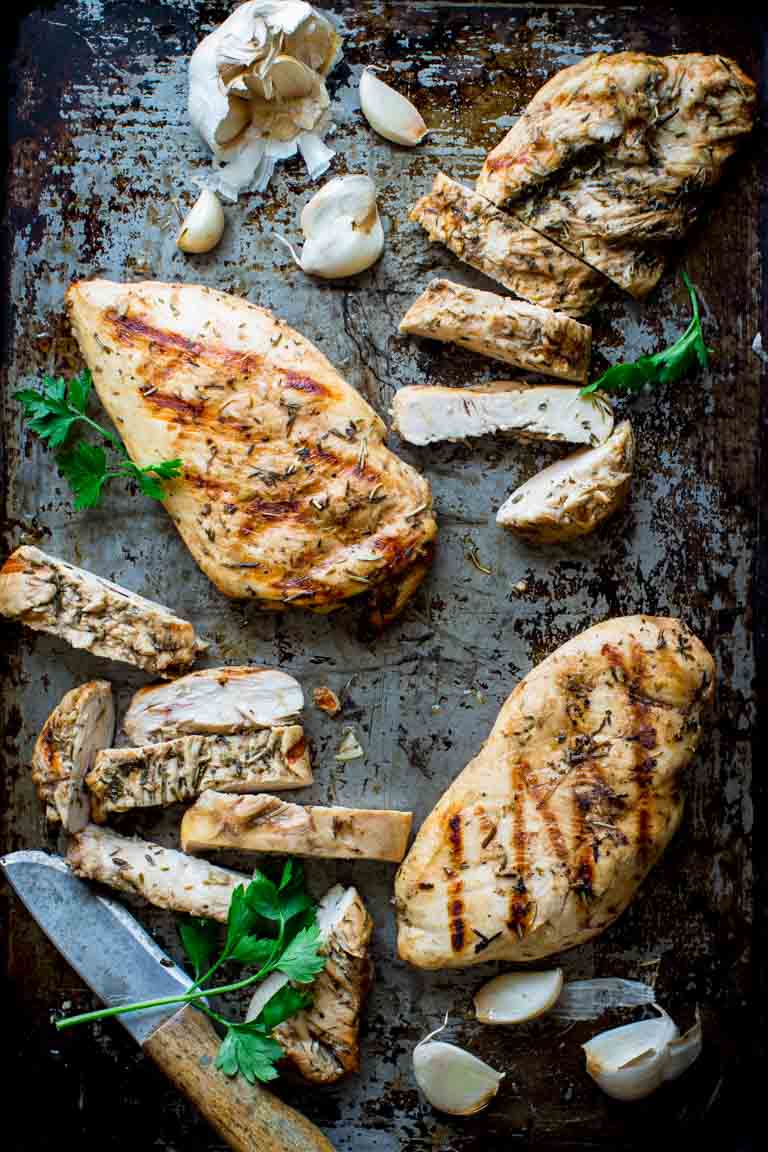 Garlic Herb Grilled Chicken on a sheet pan with a knife