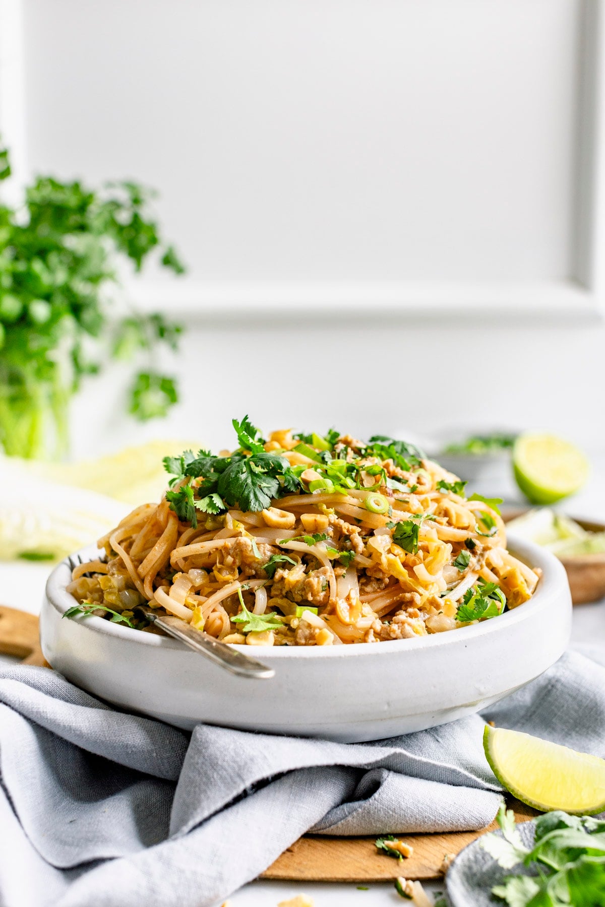 the healthy pad thai from the side with a jar of cilantro in the background
