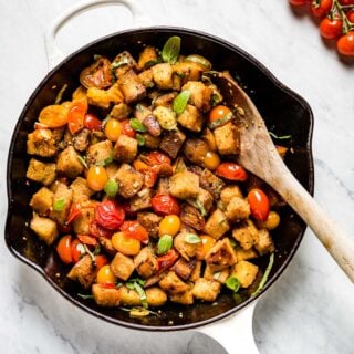 cherry tomato panzanella in a skillet with a wooden spoon
