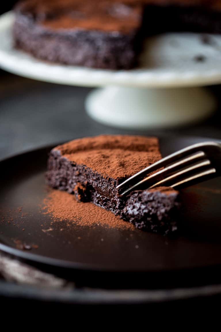 cutting into a piece of Flourless Chocolate Cake with a fork