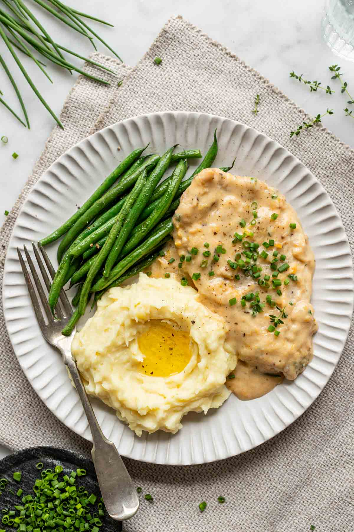 a serving of the chicken on a plate with mashed potatoes and sauteed green beans