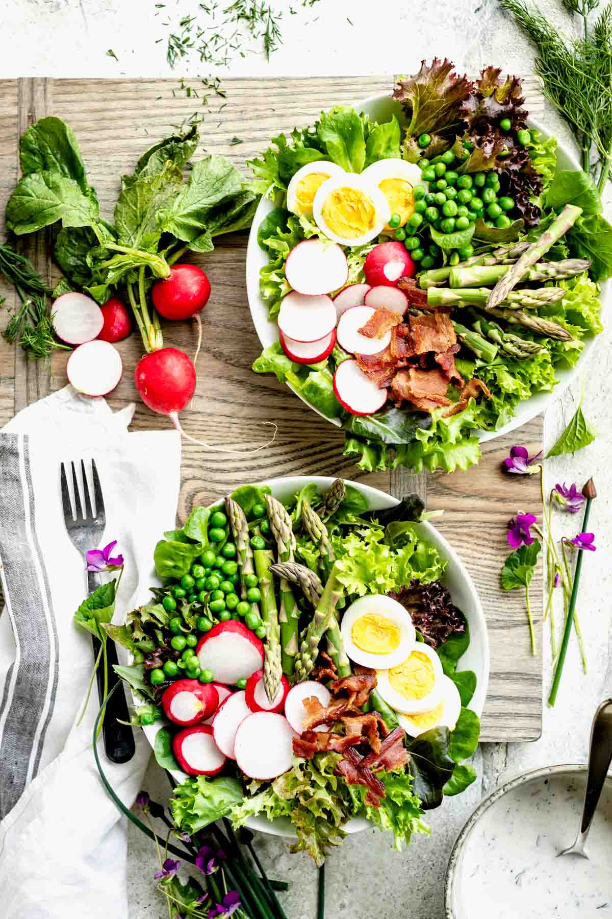 Spring Salad in two bowls on a gray cutting board from overhead