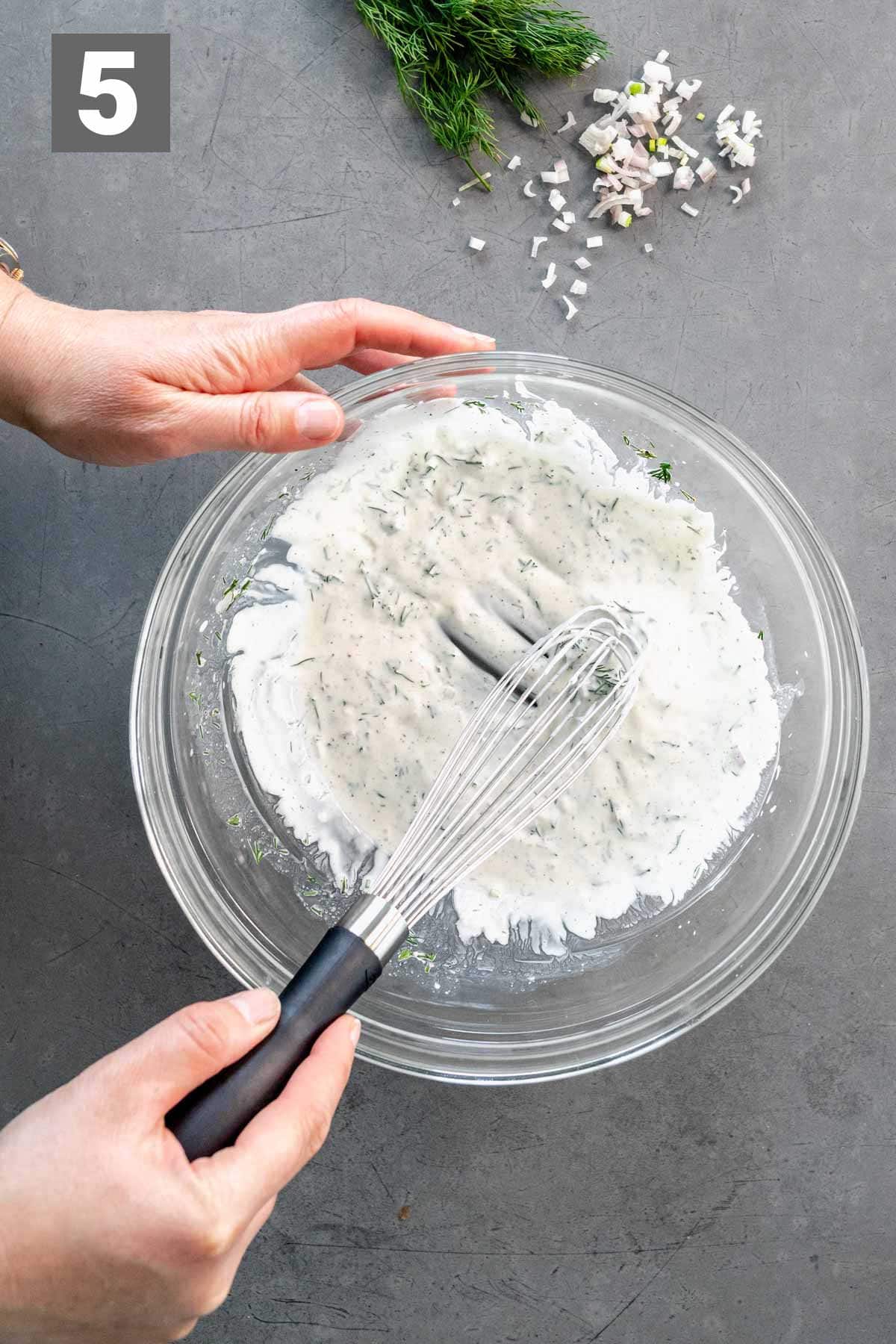 whisking the dressing in a large glass bowl