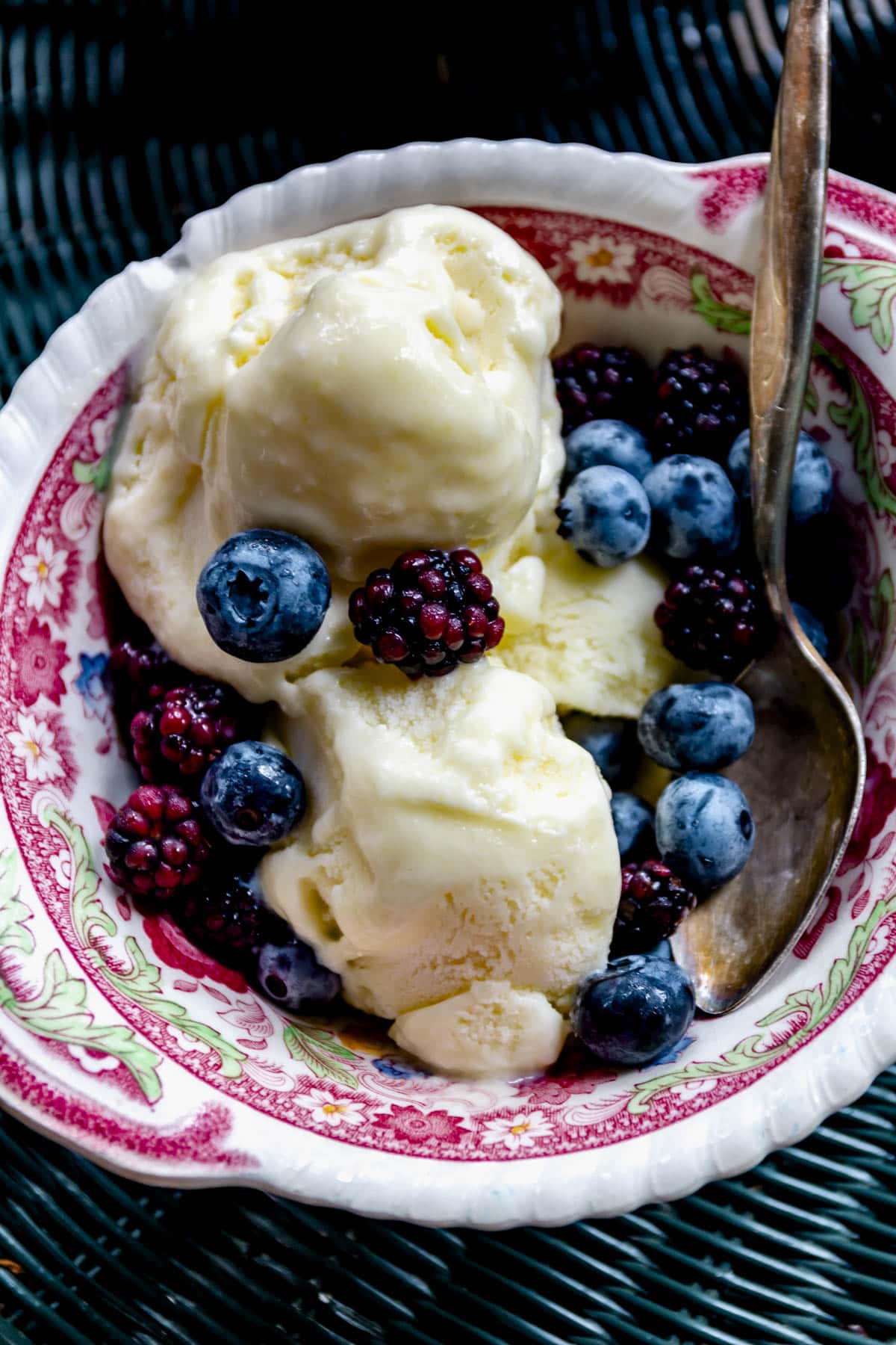 the corn ice cream in a bowl with blueberries and blackberries on top
