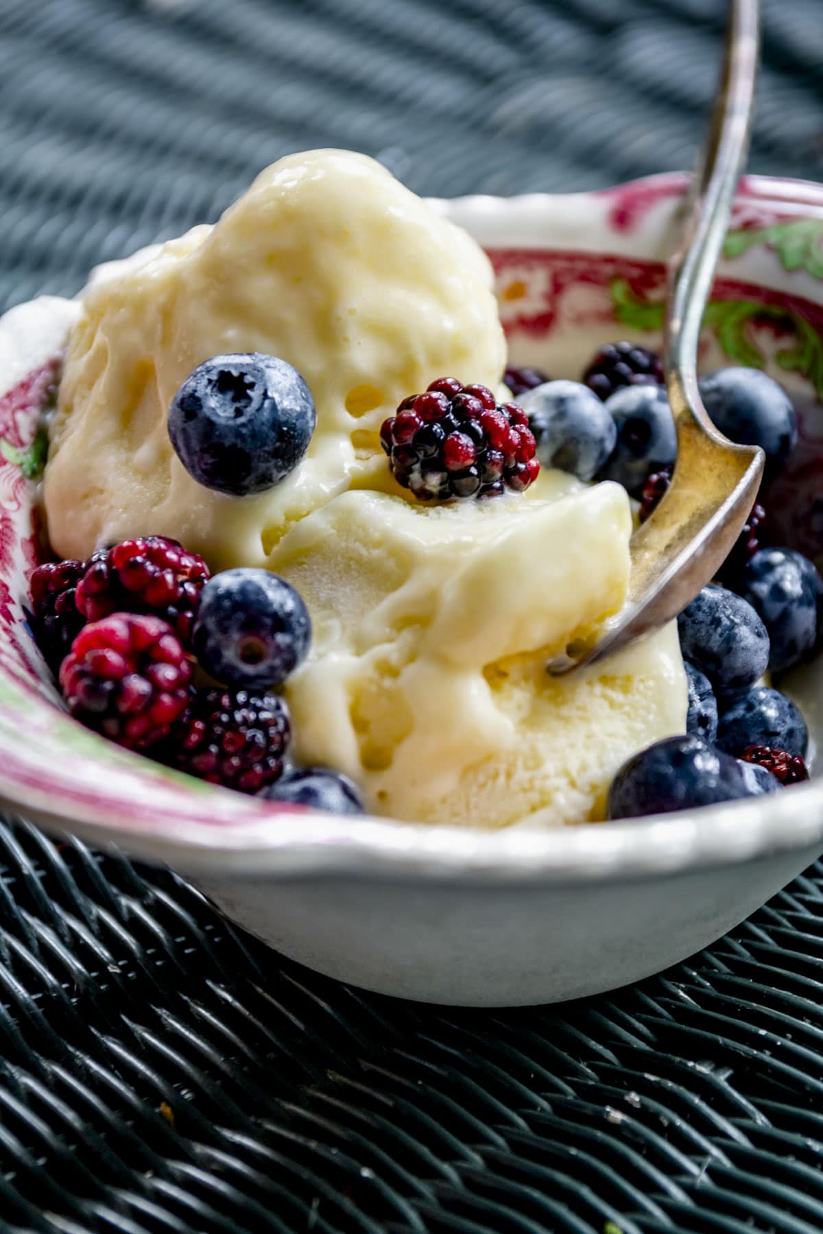 corn ice cream in a pink and white dish with fresh berries on top