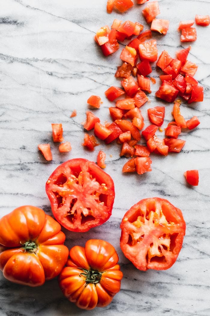 overhead of tomatoes, diced, peeled and whole on a marble board