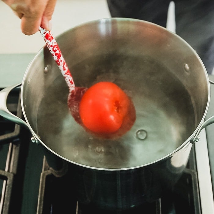 dropping a tomato into simmering water