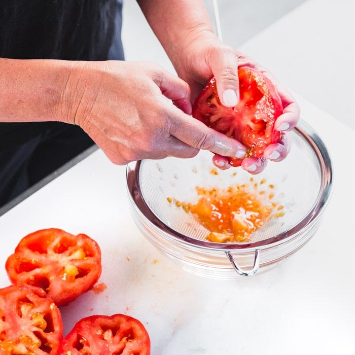 removing tomato seeds over a sieve
