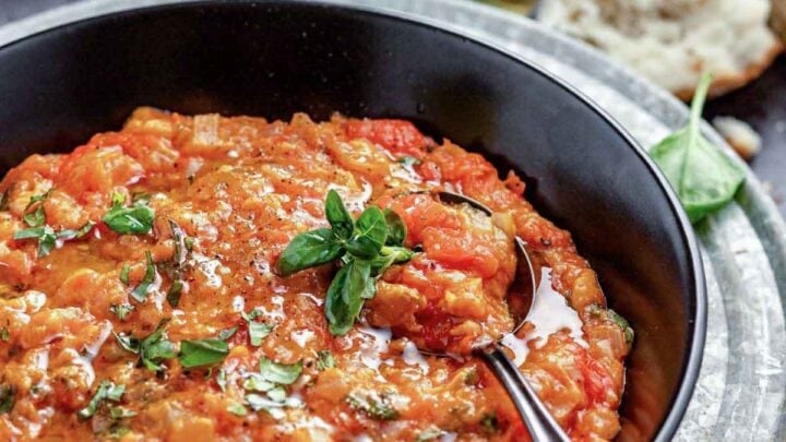the soup in a black bowl with basil sprigs
