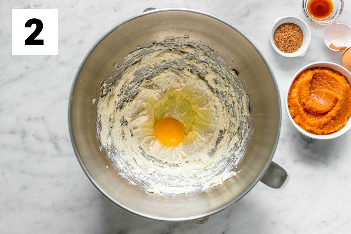 the mixing bowl with the cream cheese in it, with egg, pumpkin and spice
