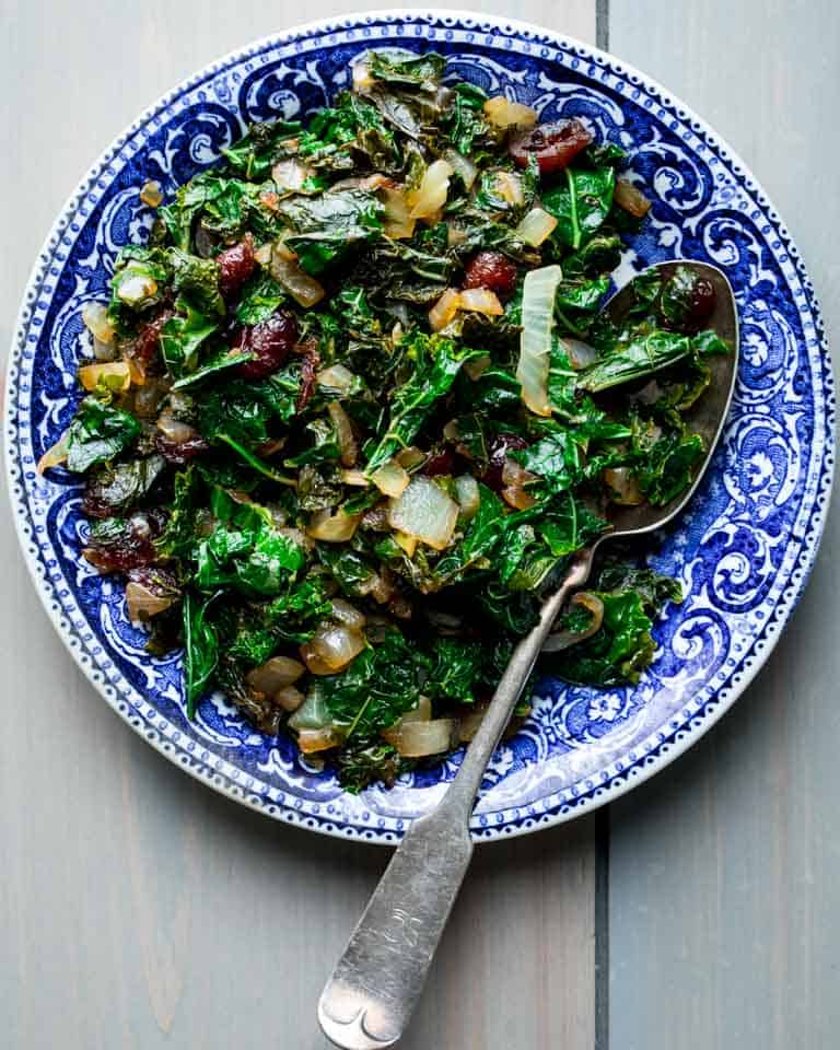 A blue bowl with sauteed kale in it
