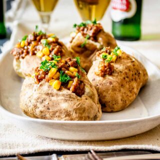 four stuffed baked potatoes with beef and corn on a platter