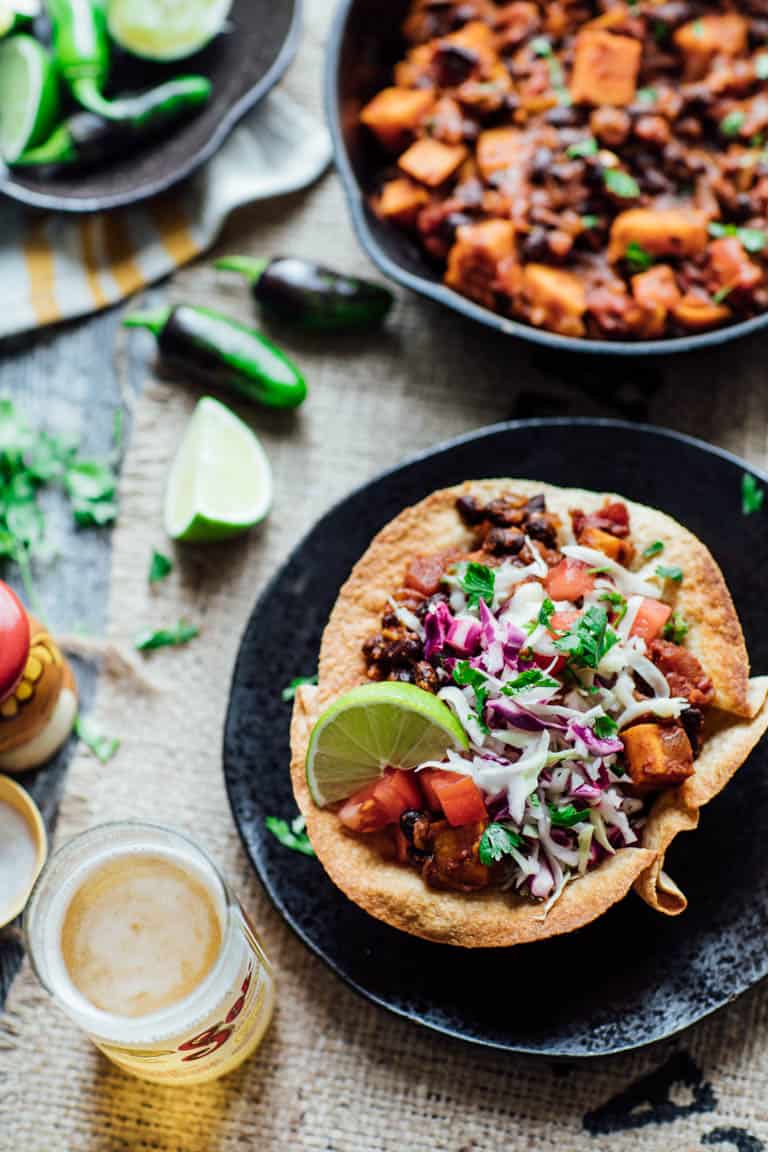 overhead view of the tortilla bowls with chili in them with a beer