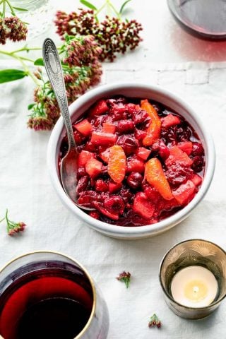 Cranberry Sauce with Orange on a white tablescape with sedum and red wine