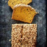 A loaf of pumpkin streusel bread, cut into slices and laid on a black patterned baking sheet