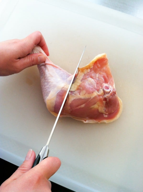 cutting the chicken thigh from the drumstick along the fat line