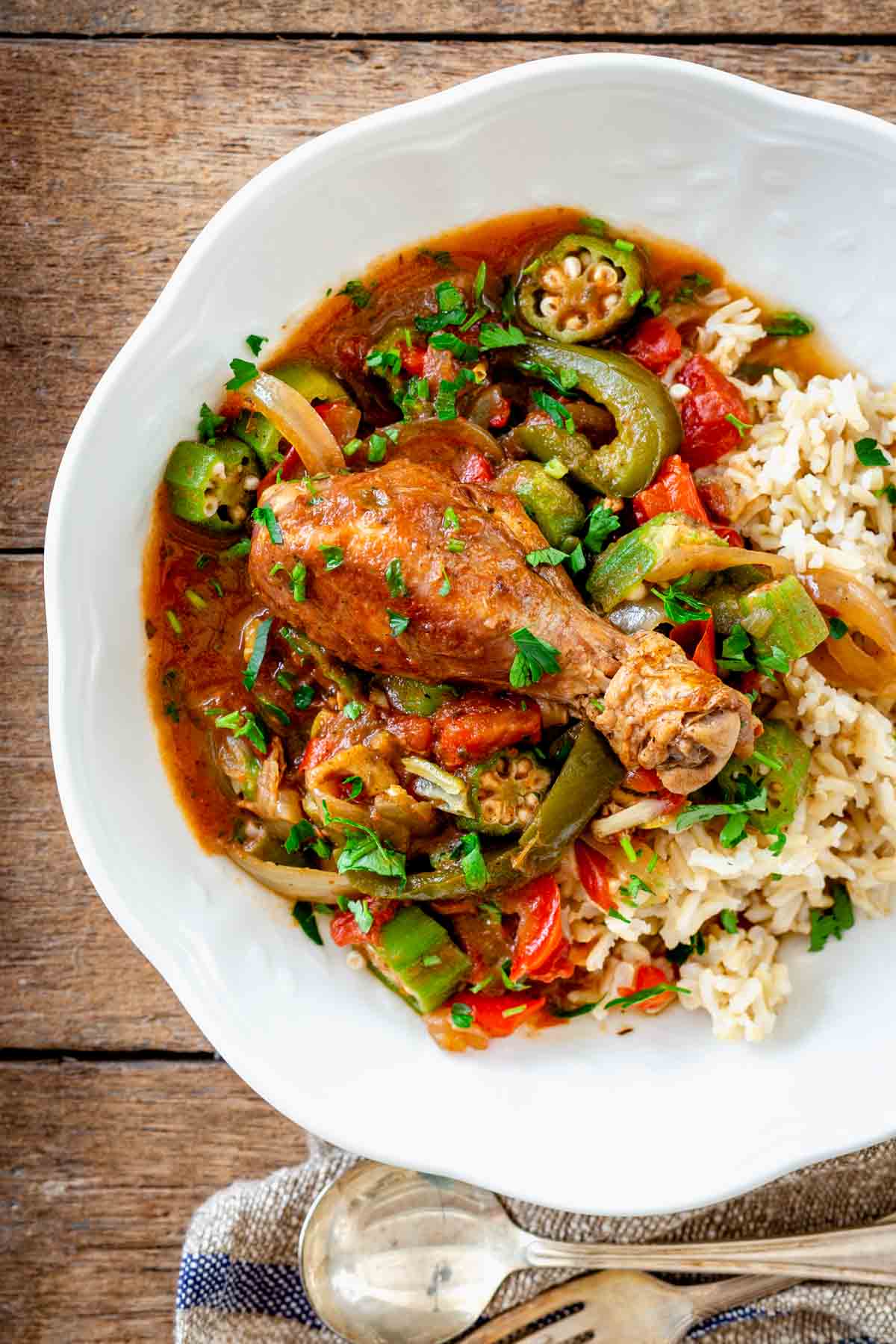 a white bowl with the braised chicken legs, peppers and okra in tomato broth