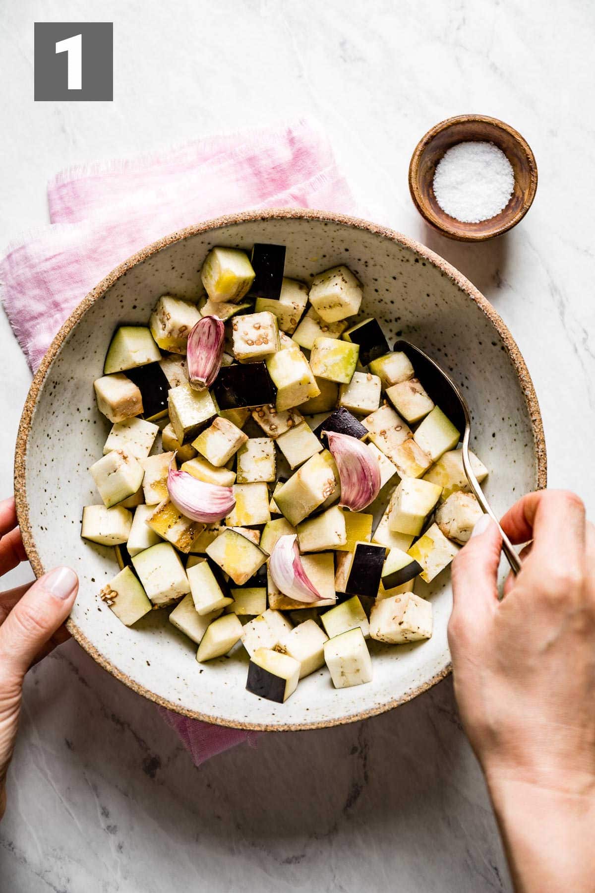 Toss the eggplant, garlic cloves, salt and oil in a bowl