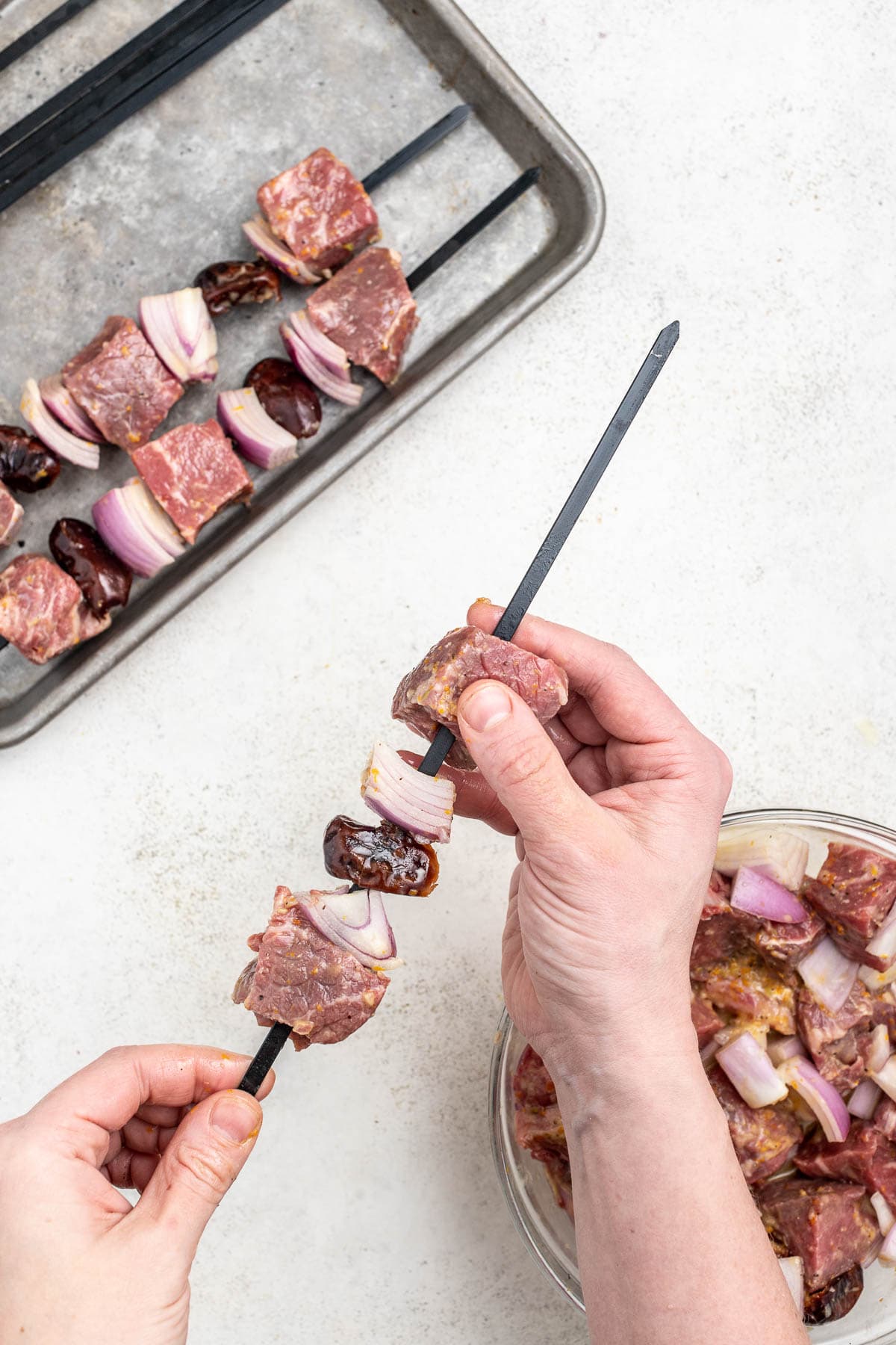 skewering the marinated beef with dates and onions