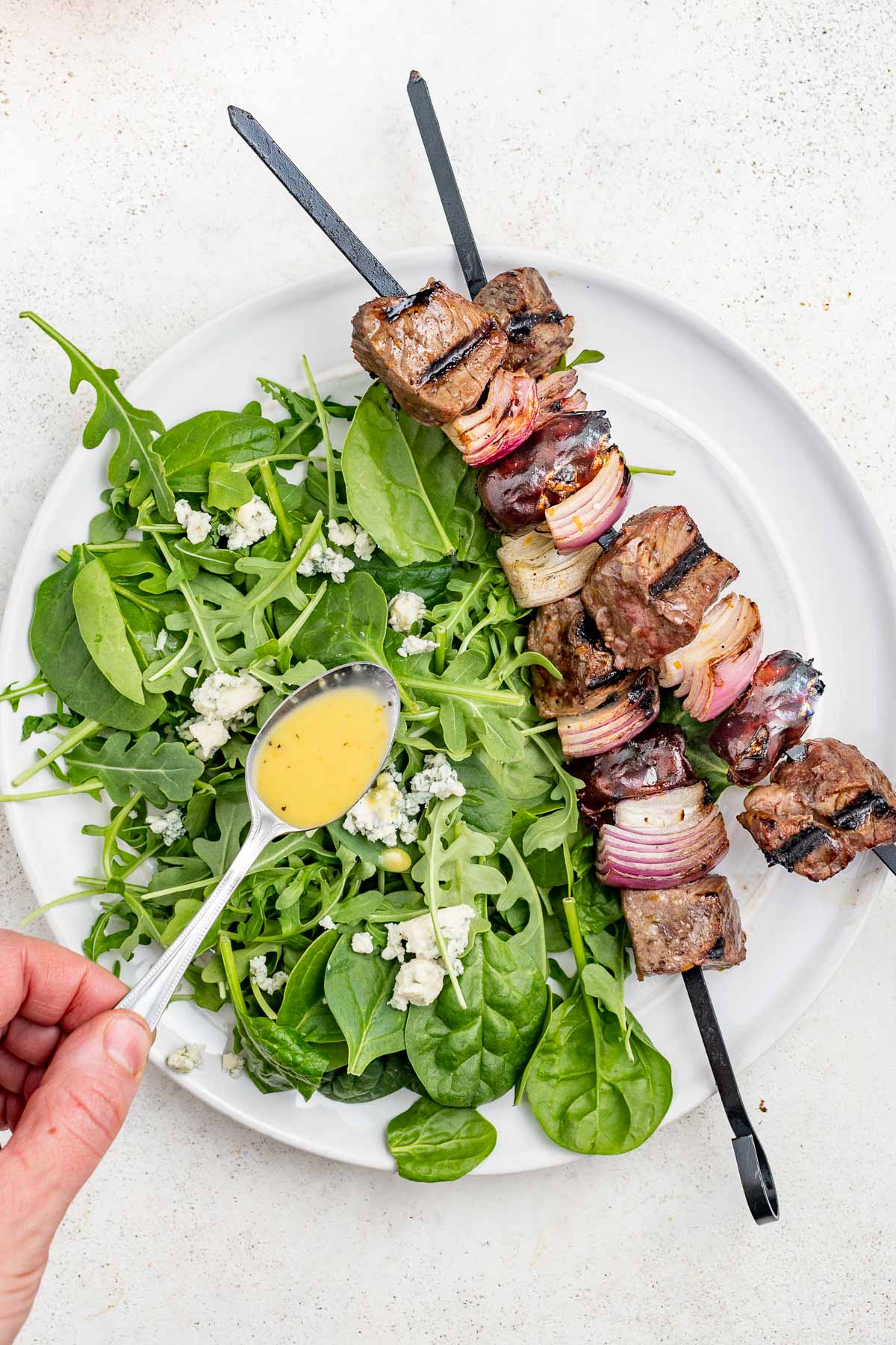 drizzle the dressing over the spinach salad and serve with the kebabs