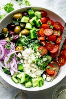 A close up view of a white bowl filled with Greek Cucumber Salad