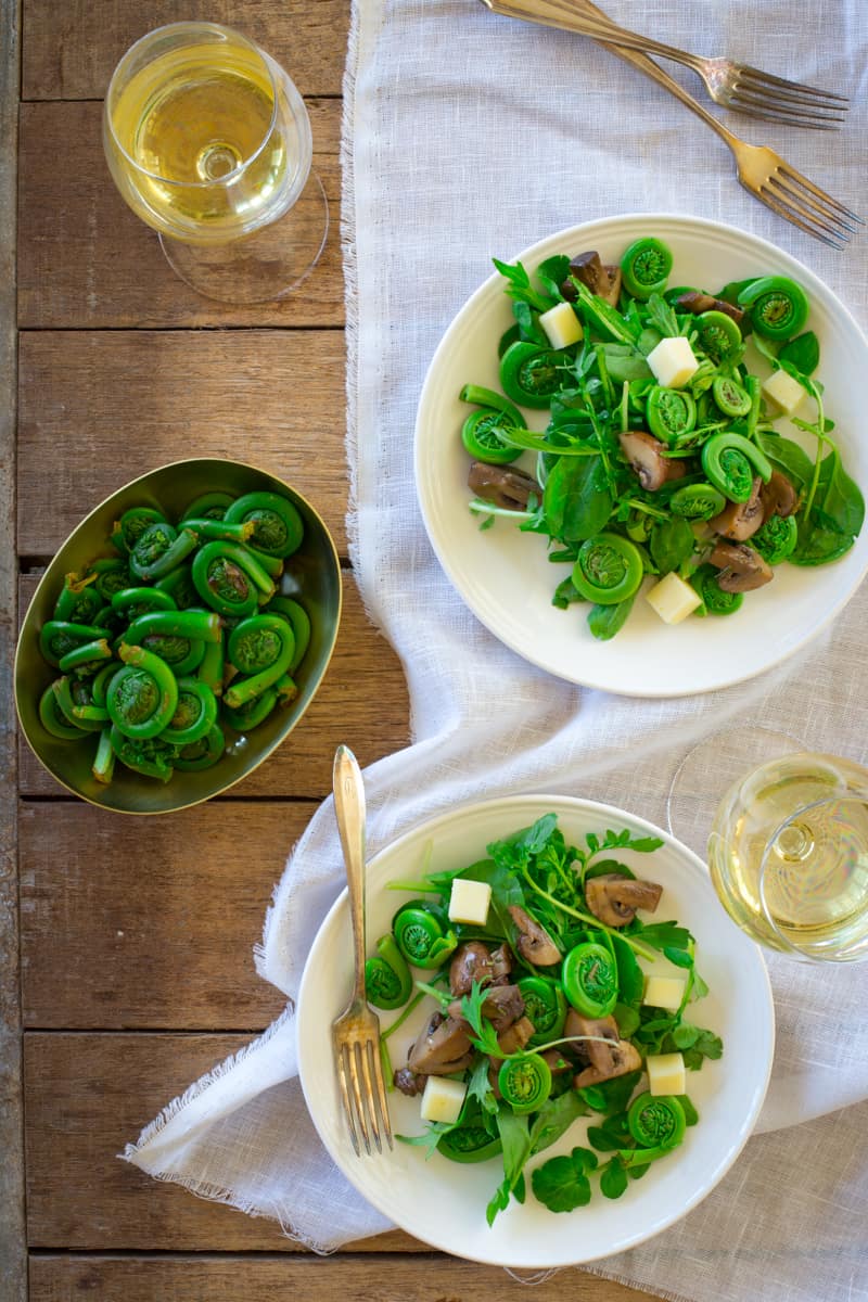 Marinated Mushroom and Fiddlehead Salad with Swiss Cheese on a plate on a table