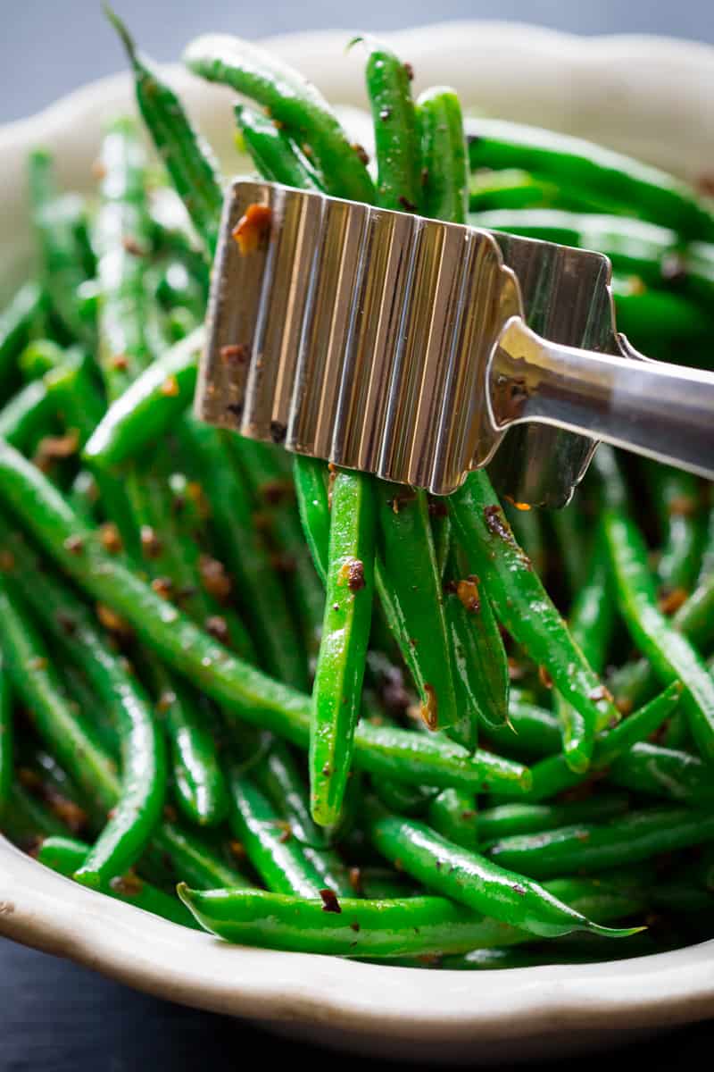 a close up of Asian Style Green Beans with tongs