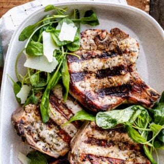 a close up of the pork chops on a platter with the salad