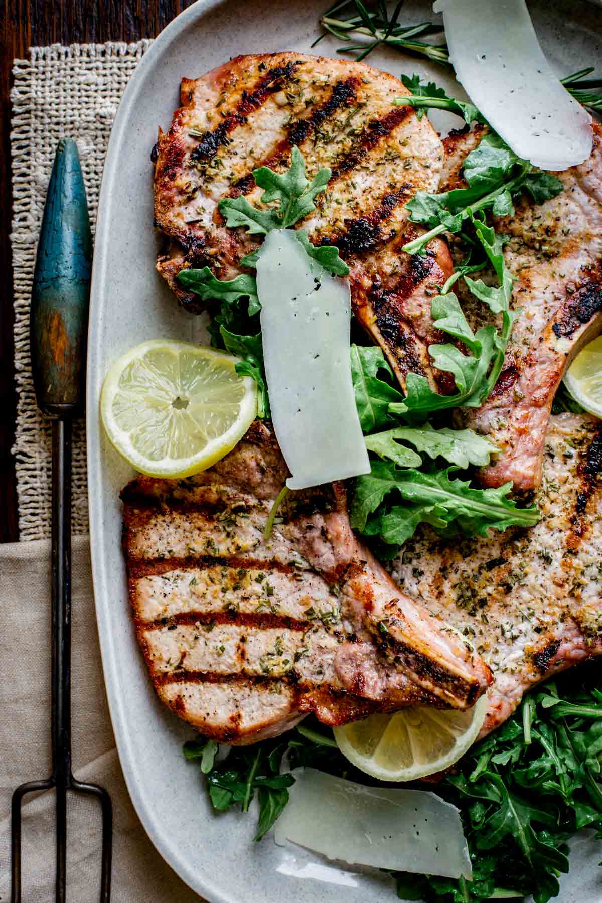 a platter of grilled pork chops with arugula salad