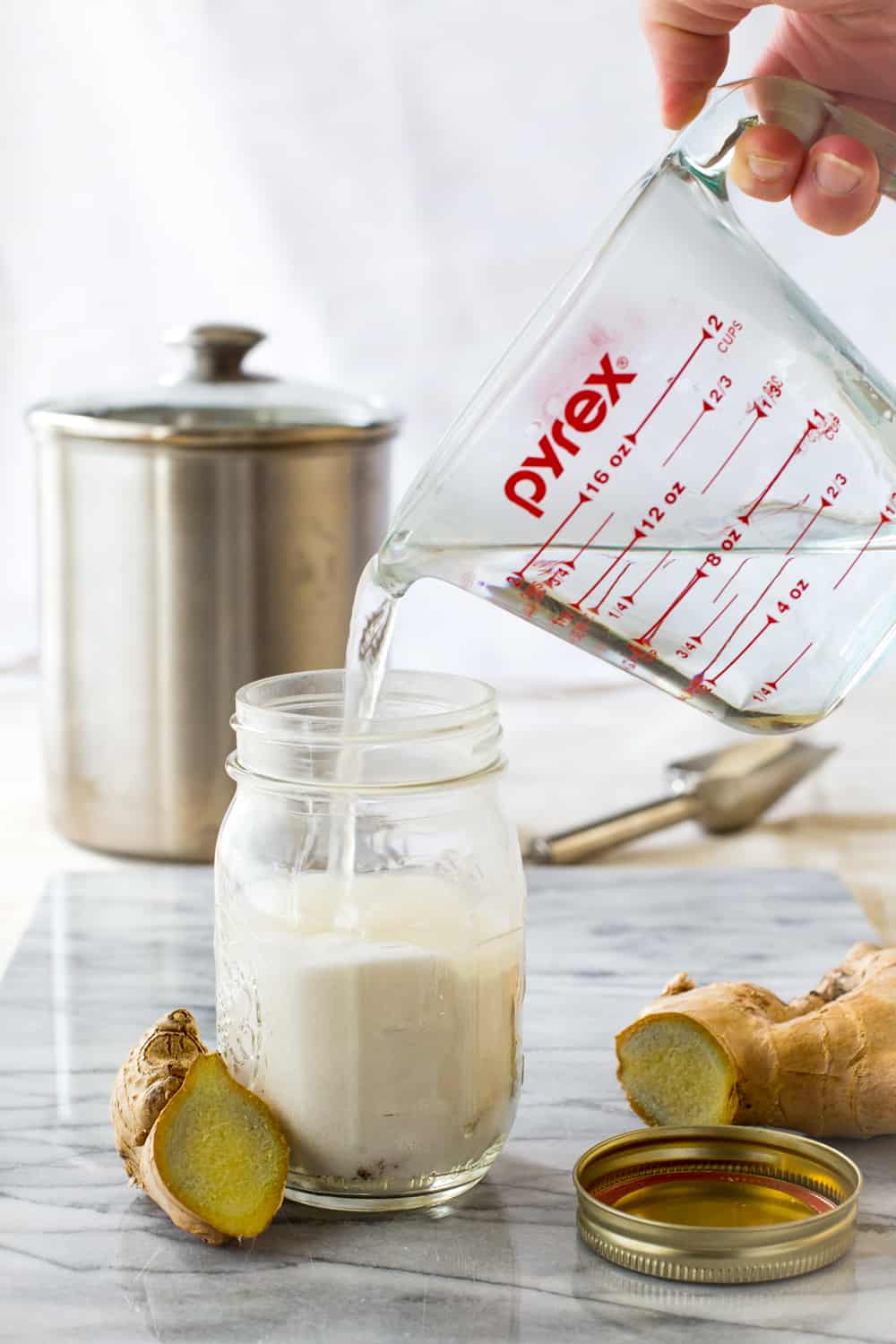 Pouring water into a jar with granulated sugar and ginger coins