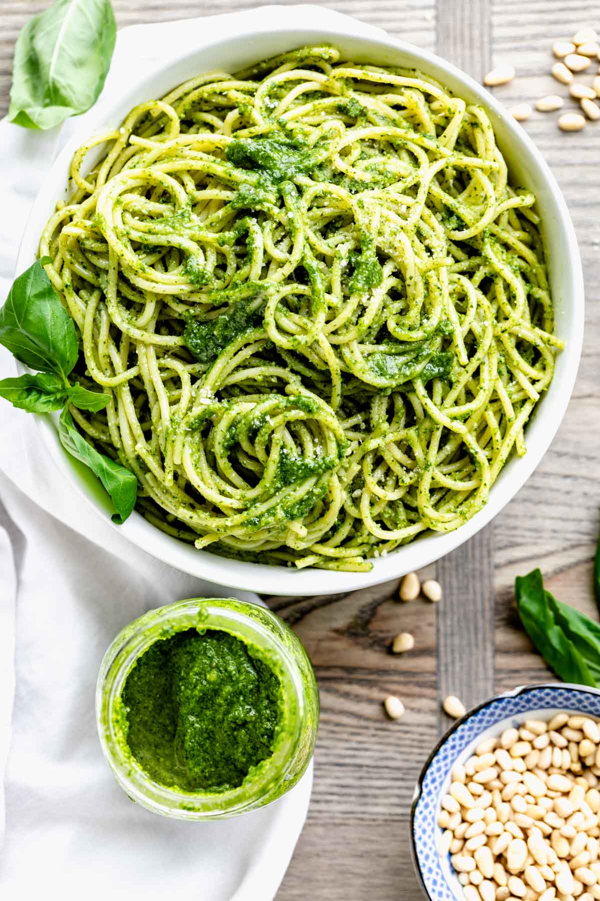 a bowl of pasta with pesto from overhead and a jar of pesto