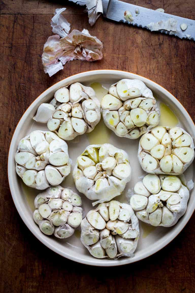 Whole garlic bulbs in a plate with olive oil