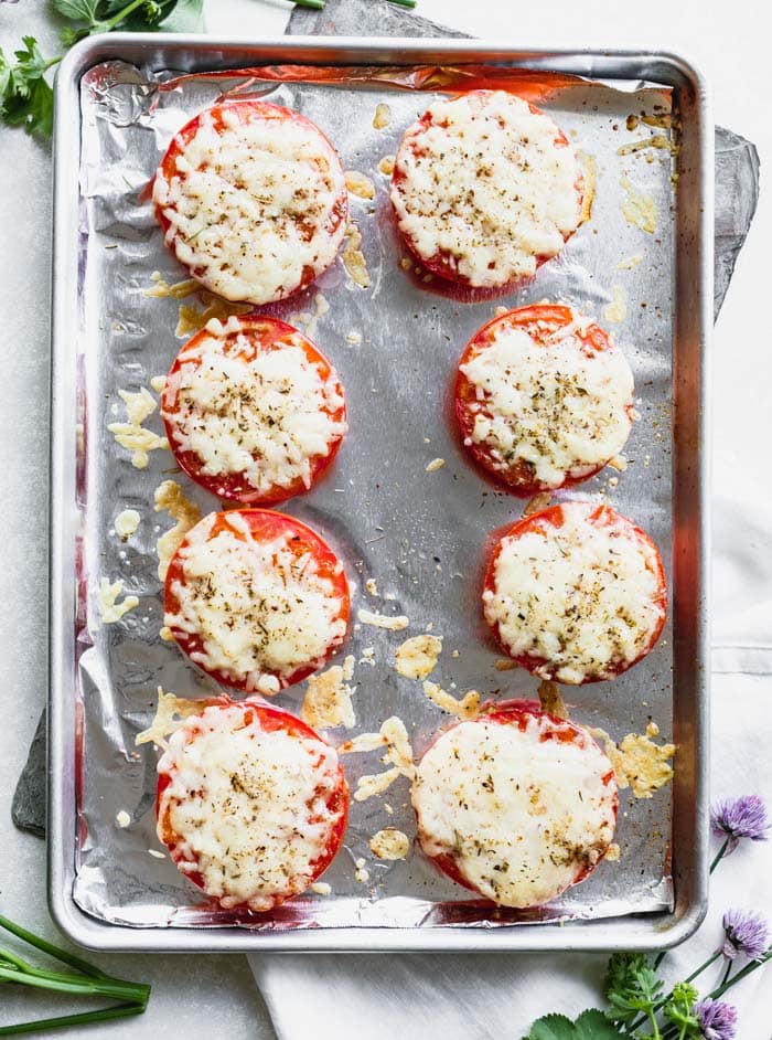 Overhead of a sheet pan with foil with cheddar tomatoes on top