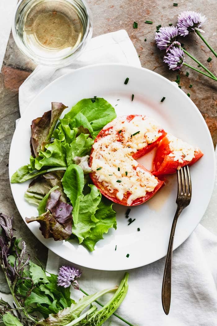 A plate with a tomato with a slice taken out